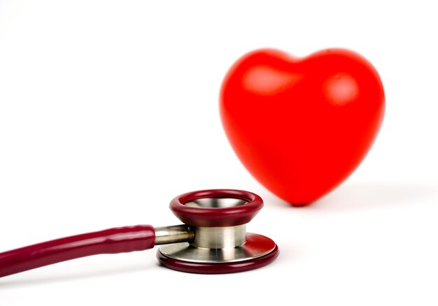 Rotes Herz mit Stethoskop auf weißem Hintergrund Selektiver Fokus Gesundheit und medizinisches Konzept
