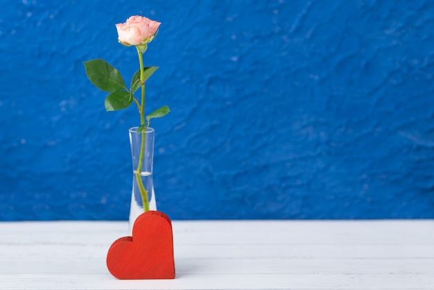 rotes Herz und Blumen im Glas auf blau