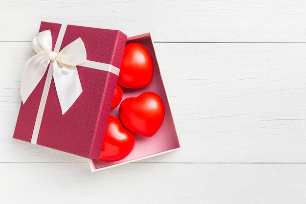 Rotes Herz und Geschenkbox der Draufsicht rotes mit Band auf weißem hölzernem Plankenhintergrund