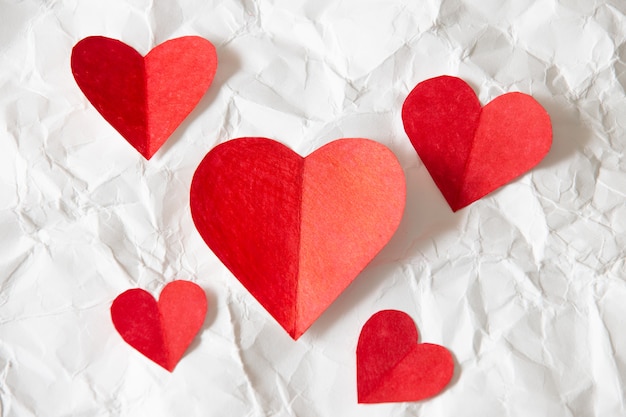 Rotes Herzpapier auf weißem zerknittertem Papier, schöner Hintergrund des Valentinstags