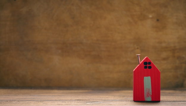 Rotes Holzhaus auf braunem Hintergrund. Konzept der Vermietung, des Kaufs und des Verkaufs von Immobilien. Maklerdienste, Gebäudereparatur und -wartung, Kopienraum