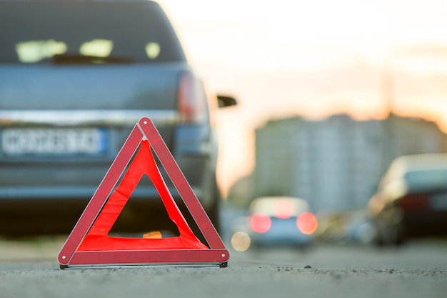 Rotes notdreieck-stoppschild und kaputtes auto auf einer stadtstraße.