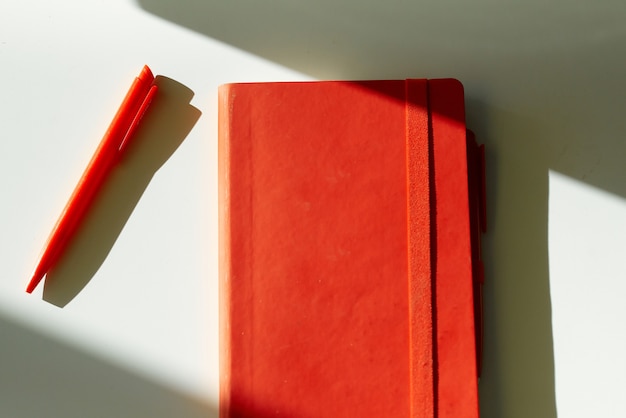 Rotes Notizbuch Notizstift Sonnenlicht weißer Tisch