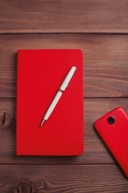 Rotes Notizbuch und ein Smartphone.