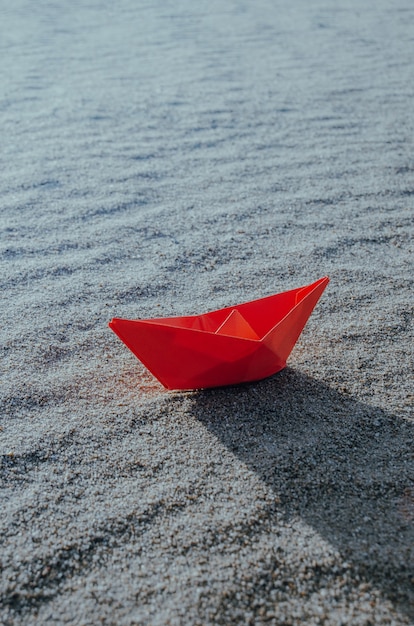 Rotes Papierboot am Grund eines trockenen Meeres. Strand, Hitze und Urlaub.Ökologie, Dürre.