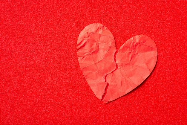Rotes Papierherz zerrissen auf zwei Stücken auf rotem Hintergrund Konzept des gebrochenen Herzens