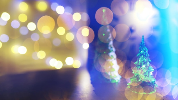 Rotes Weihnachtsbaumspielzeug auf einem Ast eines natürlichen Tannenbaums mit Lichtern von Girlanden in Unschärfe im Hintergrund. Metallspielzeug mit Schlitzen aus Hirschen und Schneeflocken. Weihnachten, neues Jahr, Kopienraum, Bokeh.