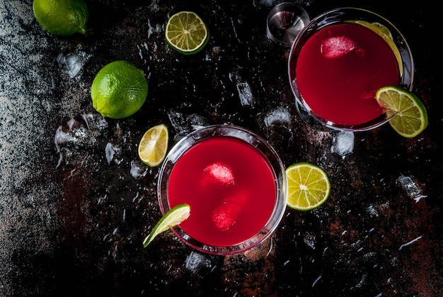 Rotes Weltcocktail mit Kalk im Martini-Glas auf dunklem rostigem Hintergrund
