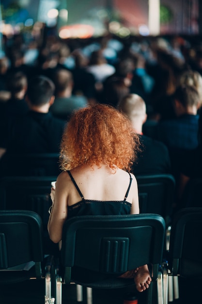 Rothaarige Frau, die auf Stuhlrückansicht sitzt