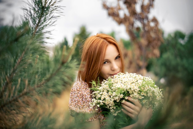 Rothaarige Frau von vierzig Jahren mit einem großen Strauß Wildblumen im Sommer in der Natur