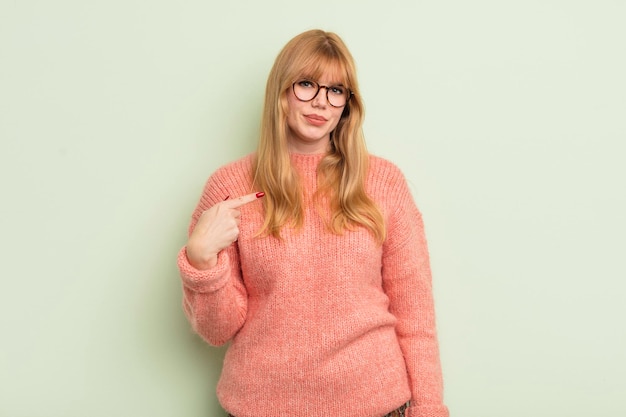 Rothaarige hübsche Frau, die stolz, selbstbewusst und glücklich aussieht, lächelt und auf sich selbst zeigt oder das Zeichen Nummer eins macht