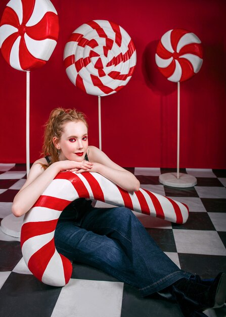 Rothaarige hübsche Frau mit riesigen Zuckerrohrbonbons in Weihnachtsdekorationen