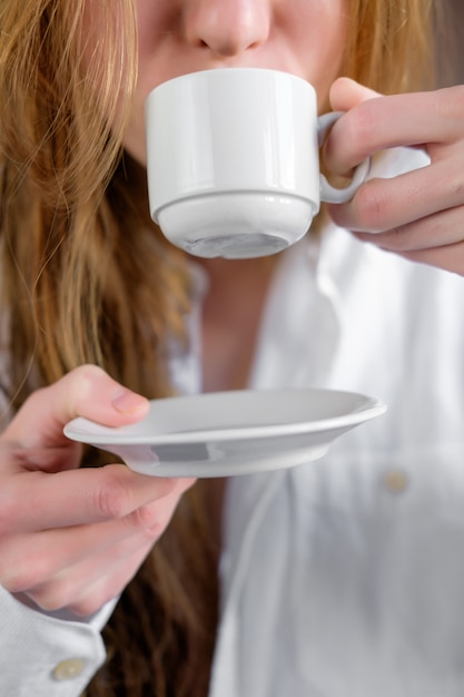 Rothaarigefrau in trinkendem Kaffee des weißen Hemdes, Abschluss oben