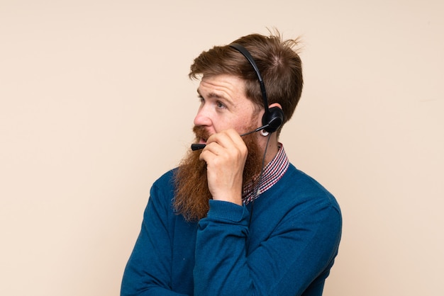 Rothaarigemann mit langem Bart über dem lokalisierten Hintergrund, der mit Kopfhörer arbeitet