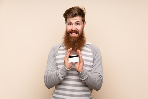 Rothaarigemann mit langem Bart über der lokalisierten Wand, die eine Kreditkarte hält