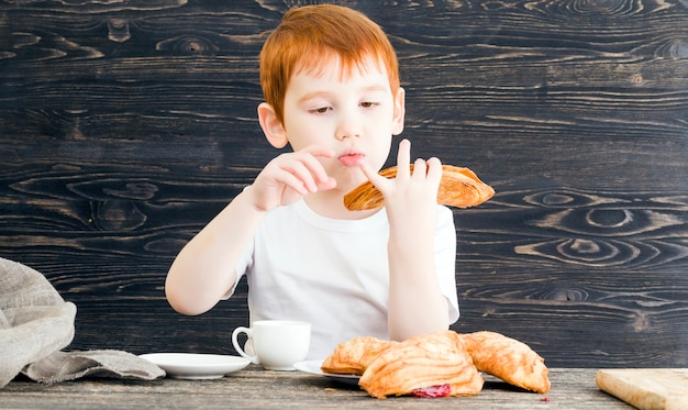 Rothaariger Junge mit süßen Brötchen mit fruchtroter Füllung, Nahaufnahme der Arbeit in der Küche