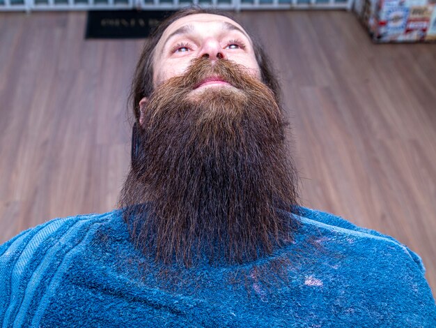 Rothaariger Mann, der im Friseurstuhl sitzt und seinen schönen abgeschnittenen Bart zeigt.