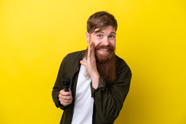Rothaariger Mann mit Bart, der ein Mikrofon aufnimmt, das auf gelbem Hintergrund isoliert ist und etwas flüstert