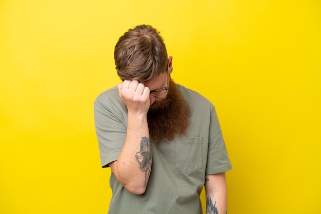 Rothaariger Mann mit Bart isoliert auf gelbem Hintergrund mit Kopfschmerzen