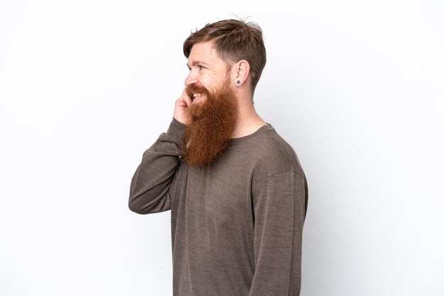 Rothaariger Mann mit Bart isoliert auf weißem Hintergrund, der mit jemandem ein Gespräch mit dem Handy führt