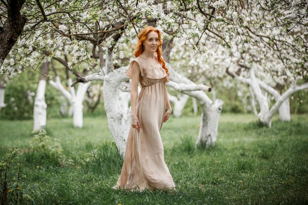 Rothaariges Mädchen in einem beigen Kleid im Garten