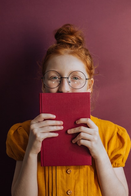 Rothaariges Mädchen mit Brille und Buch