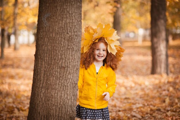 Rothaariges Mädchen mit einem Kranz aus Herbstblättern auf dem Kopf