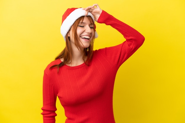 Rothaariges Mädchen mit Weihnachtsmütze auf gelbem Hintergrund isoliert