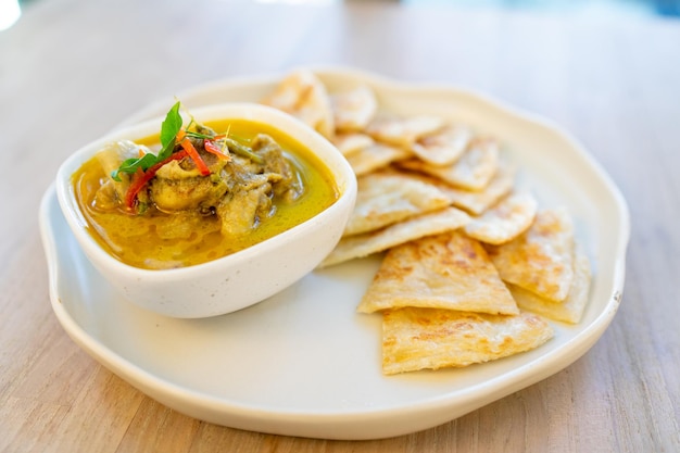 Roti crocante servido com curry verde com frango na mesa de madeira