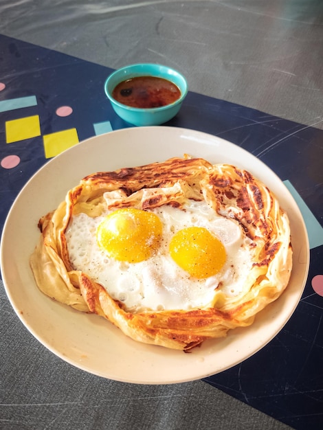 Foto roti sarang burung en la mesa es pratha parece un nido de pájaro medio cocinar huevos en el medio