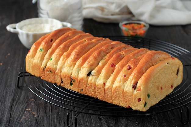 Roti Sisir Fruchtiges Weißbrot mit Trockenfrüchten und Rosinen für Weihnachtsgebäck. Auf Drahtgestell, isoliert auf Schwarz