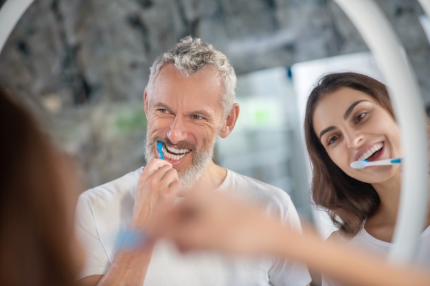 Rotina matinal. um homem e uma mulher gostando de escovar os dentes