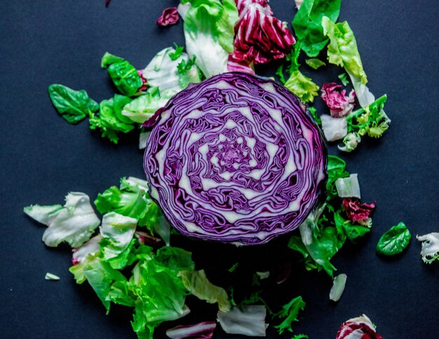 Rotkohl und andere Salate auf dunkler Oberfläche. Ansicht von oben