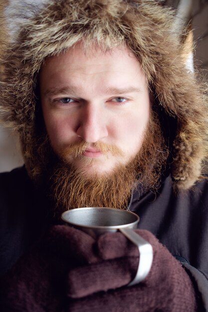 Rotschopf bärtiger Mann in der Polarjacke, die Tasse heißen Kaffee oder Tee hält