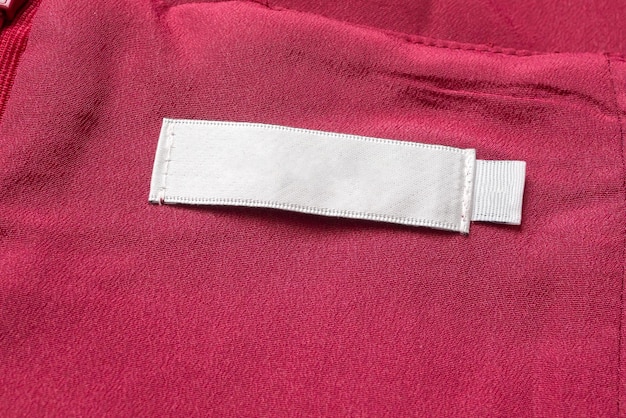 Rótulo branco de roupas de lavagem em branco em fundo de textura de tecido vermelho