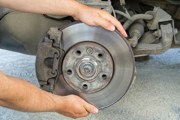 Rotura del volquete trasero viejo y sucio del vehículo para su reparación. Frenos en un automóvil con rueda eliminada. Imagen detallada de los automóviles rompen el ensamblaje antes de la reparación.