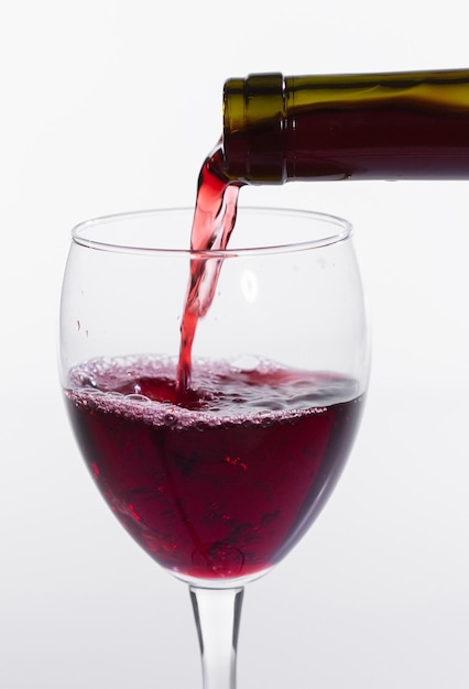 Rotwein in das Glas auf weißem Hintergrund gießen, Nahaufnahme