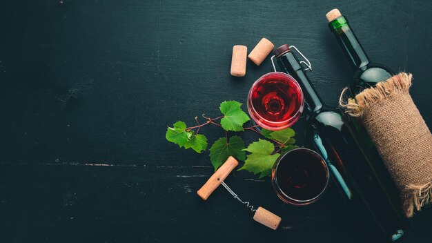 Rotwein in einer Flasche mit Glas und Trauben auf schwarzem Holzhintergrund Freier Platz für Text Ansicht von oben