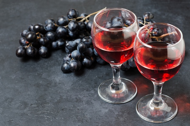 Rotwein in Gläsern, eine Reihe von schwarzen Trauben.