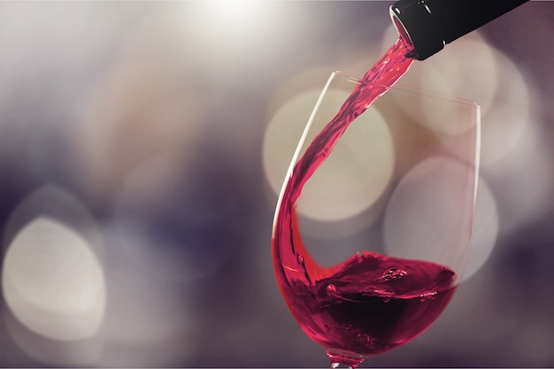 Rotwein in Glas auf den Hintergrund gießen