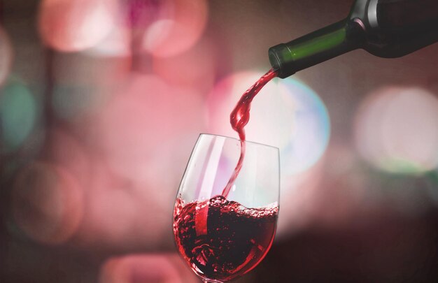 Rotwein in Glas auf dunklem Hintergrund gießen