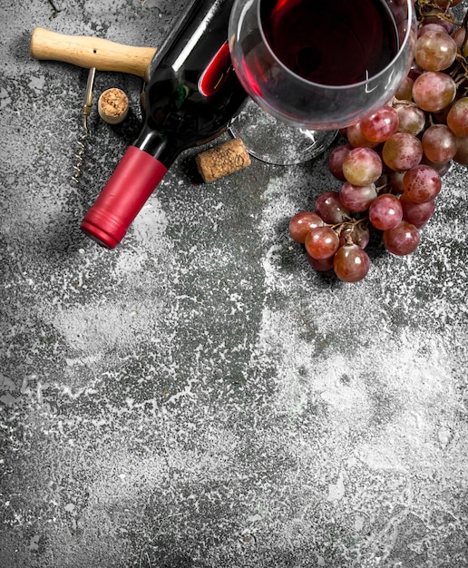 Foto rotwein mit korkenzieher. auf einem rustikalen hintergrund.