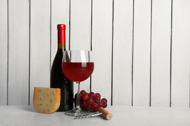 Rotwein mit Trauben und Käse auf Holzwandhintergrund