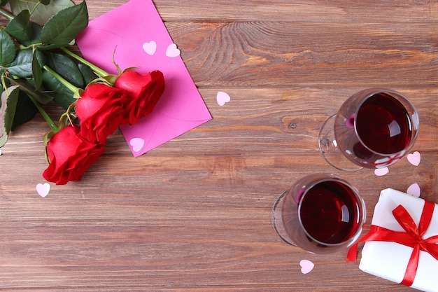 Rotwein und Rosen auf dem Tischvalentinstaghintergrund