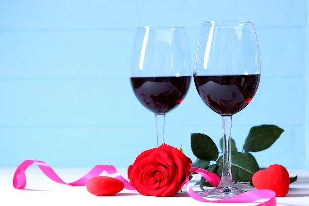 Rotwein und Rosen auf dem Tischvalentinstaghintergrund