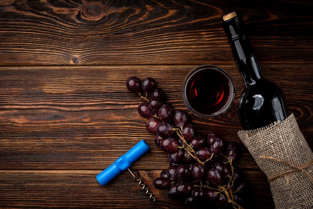 Rotwein und Traube auf dunklem hölzernem Hintergrund.