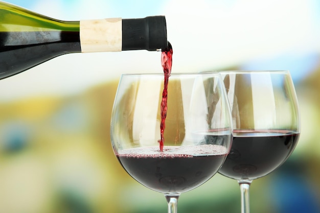 Rotwein wird auf hellem Hintergrund in Weinglas gegossen