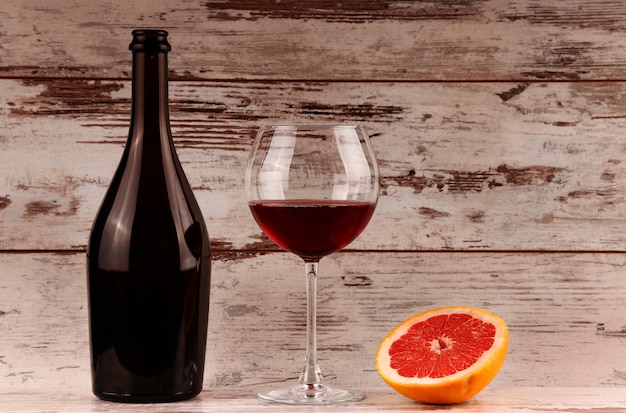 Rotweinflasche auf Holz, Apfel und Granatapfel