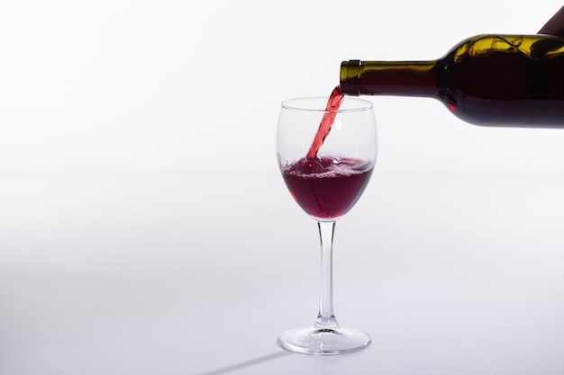 Rotweinflasche gießen Glas auf weißem Hintergrund mit Kopienraum