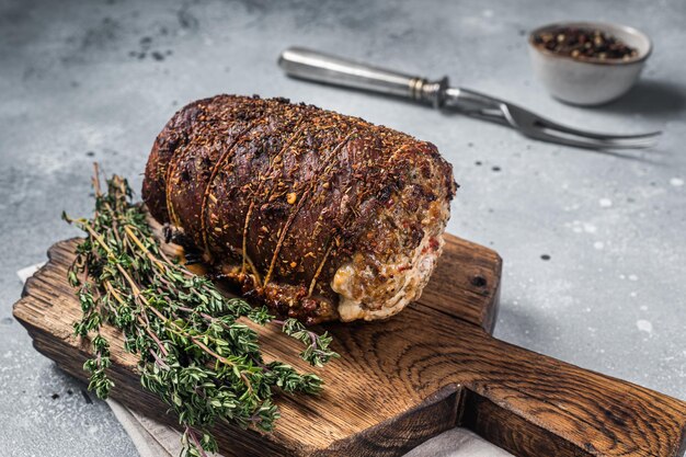 Roulade de cerdo asado Porchetta harina de carne de cerdo sobre una tabla de madera Fondo gris Vista superior